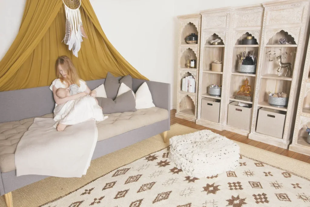 kvinne som ammer babyen sin pรฅ en sofa med ullputer