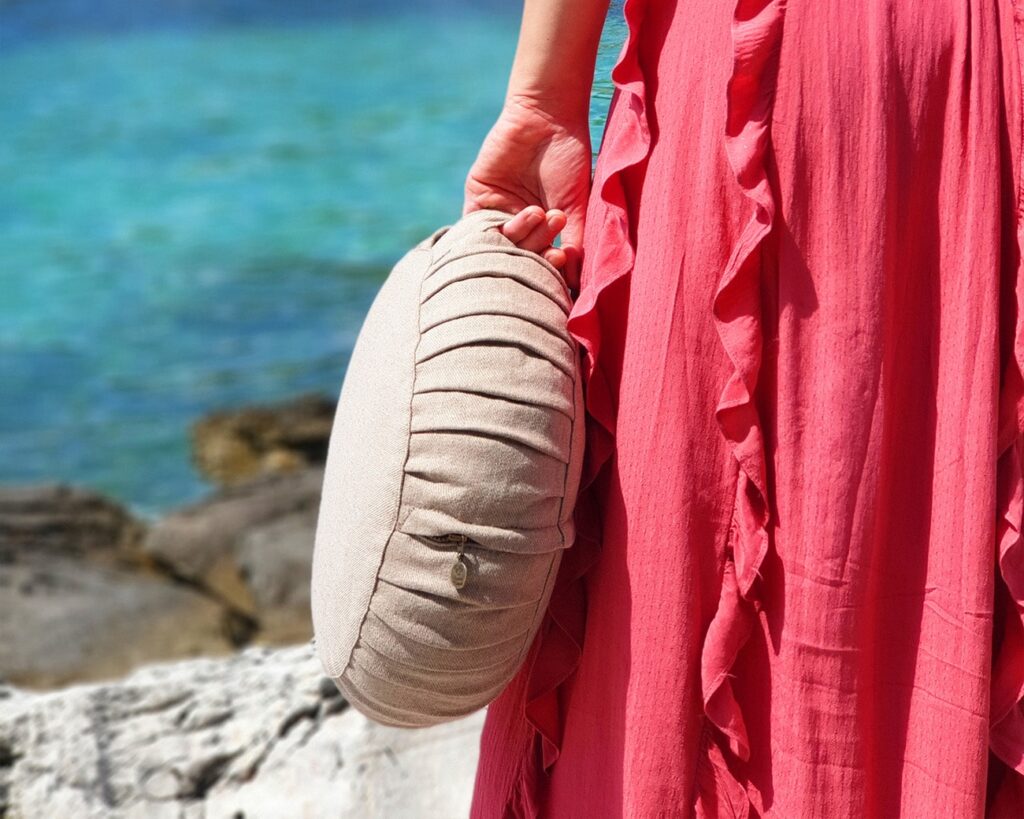 kvinne i rød kjole som bærer en meditasjonspute av ull 