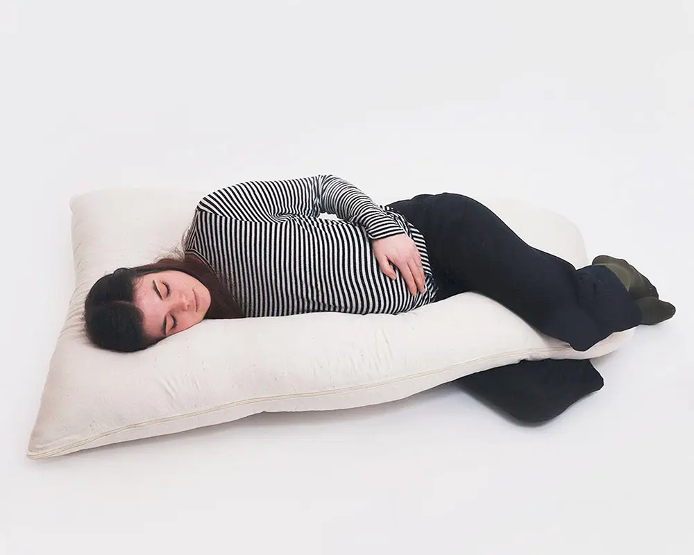 Femme dormant sur un oreiller latéral pour femmes enceintes