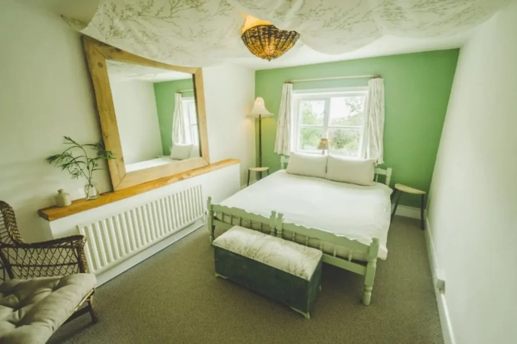 koselig, mykt grønt rom med seng med ullmadrass og ullputer og et stort speil