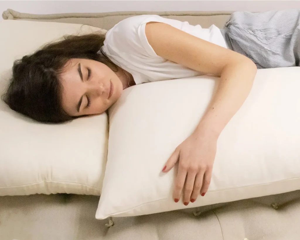 woman sleeping on a wool mattress on a wool pillow while hugging a wool pillow