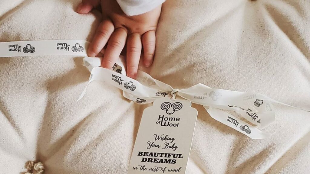 baby's hand on home of wool mattress with branded labels