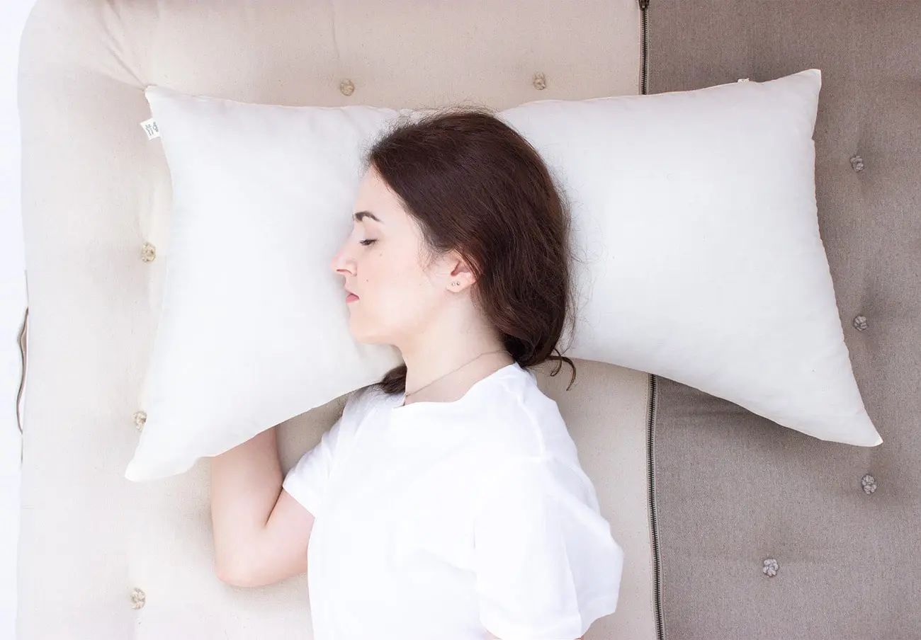 modello che dorme su un cuscino curvo per il sonno laterale - dall'alto