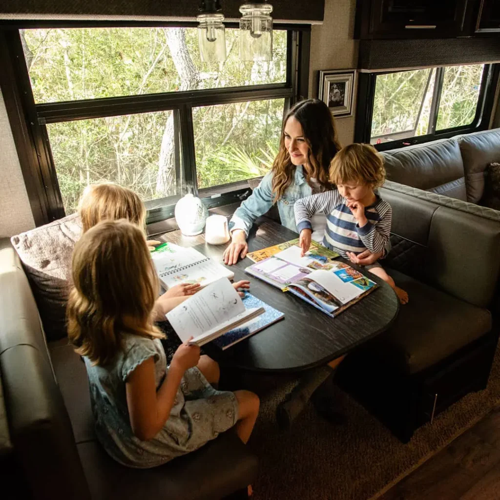 a mother and 3 children sitting at a table while reading books