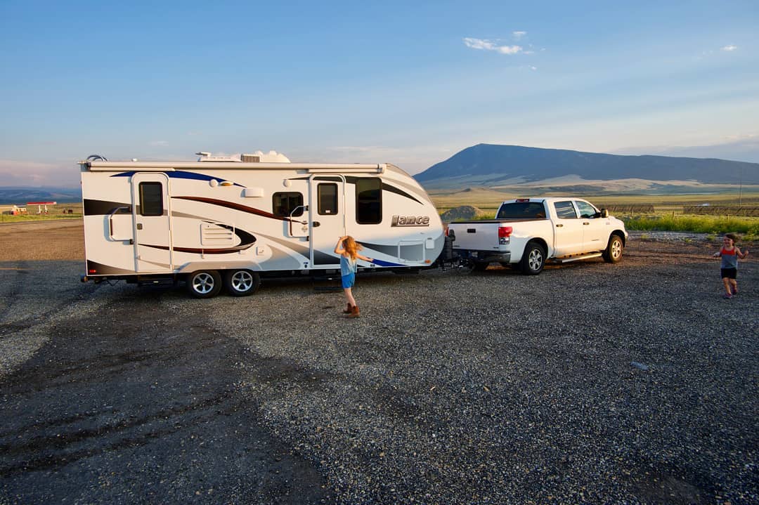 girl standing in front of an rv being pulled by a truck