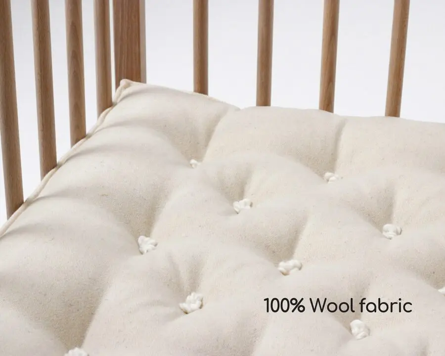 Kinderbettmatratze in einem Kinderbett mit Wollstoffbezug