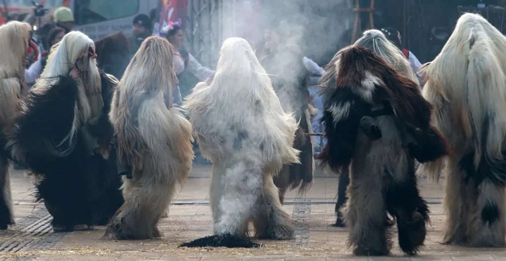 people in costumes doing the bulgarian kukeri tradition in a circle