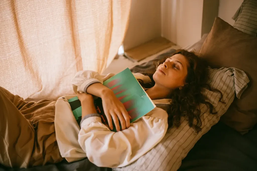 woman hugging a book while laying on a bed