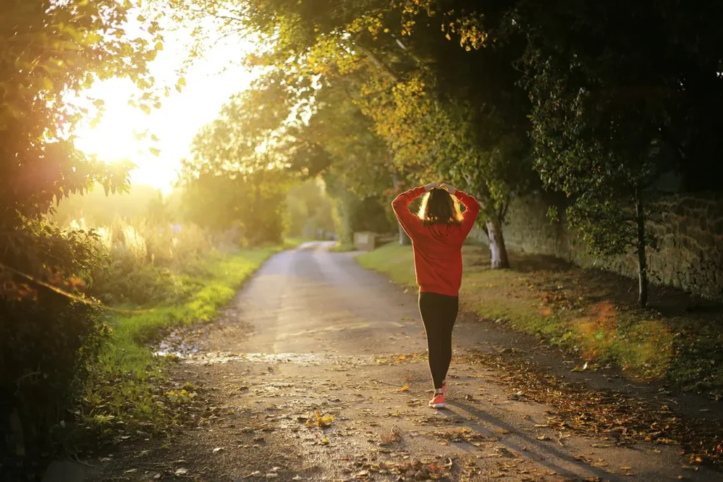 woman walking on a pavement path surrounded with trees