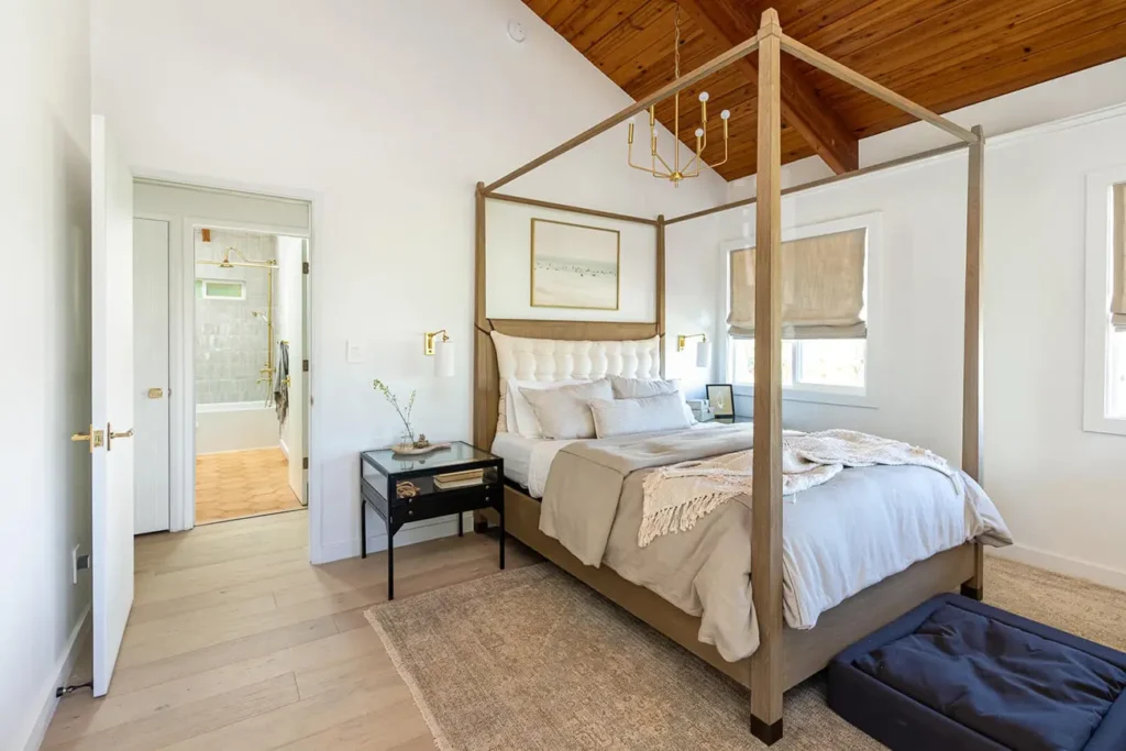 cozy room with a large bed frame with a wool bed, a duvet and many pillows