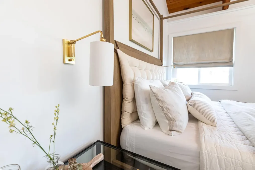 cozy room with a large bed frame with a wool bed, a duvet and many pillows