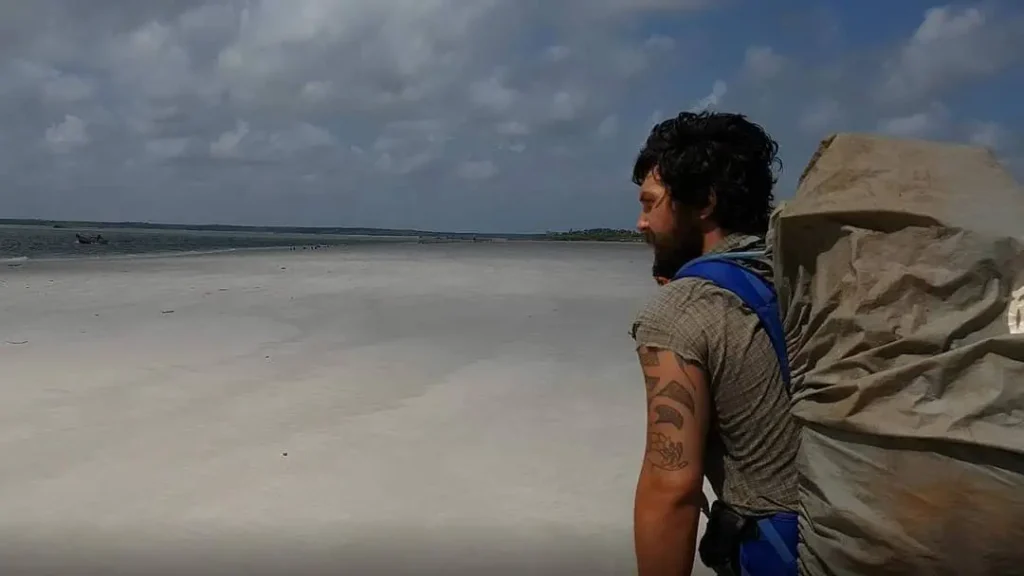 man med stor ryggsäck som tittar på havet