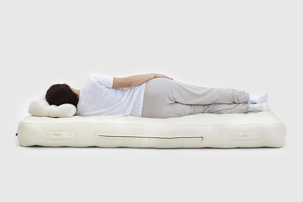 nainen makaa villapatjalla ergonomisella tyynyllä