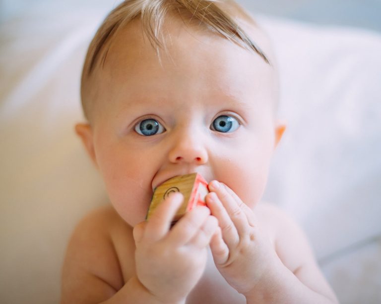 baby sucking on a wood cube