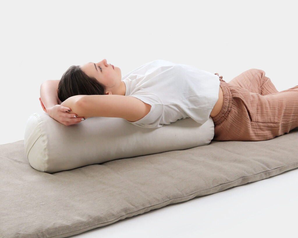 woman resting on a yoga bolster behind her back
