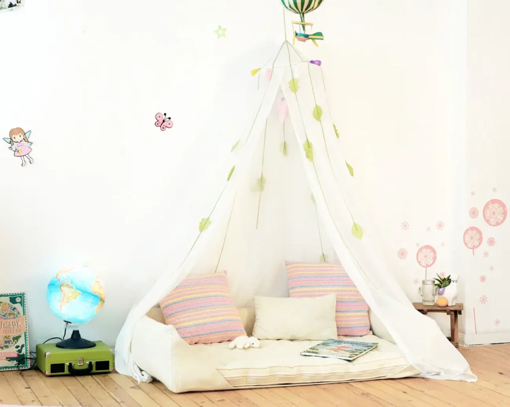 legeplads med uldmontessori-babyseng og hvid baldakin