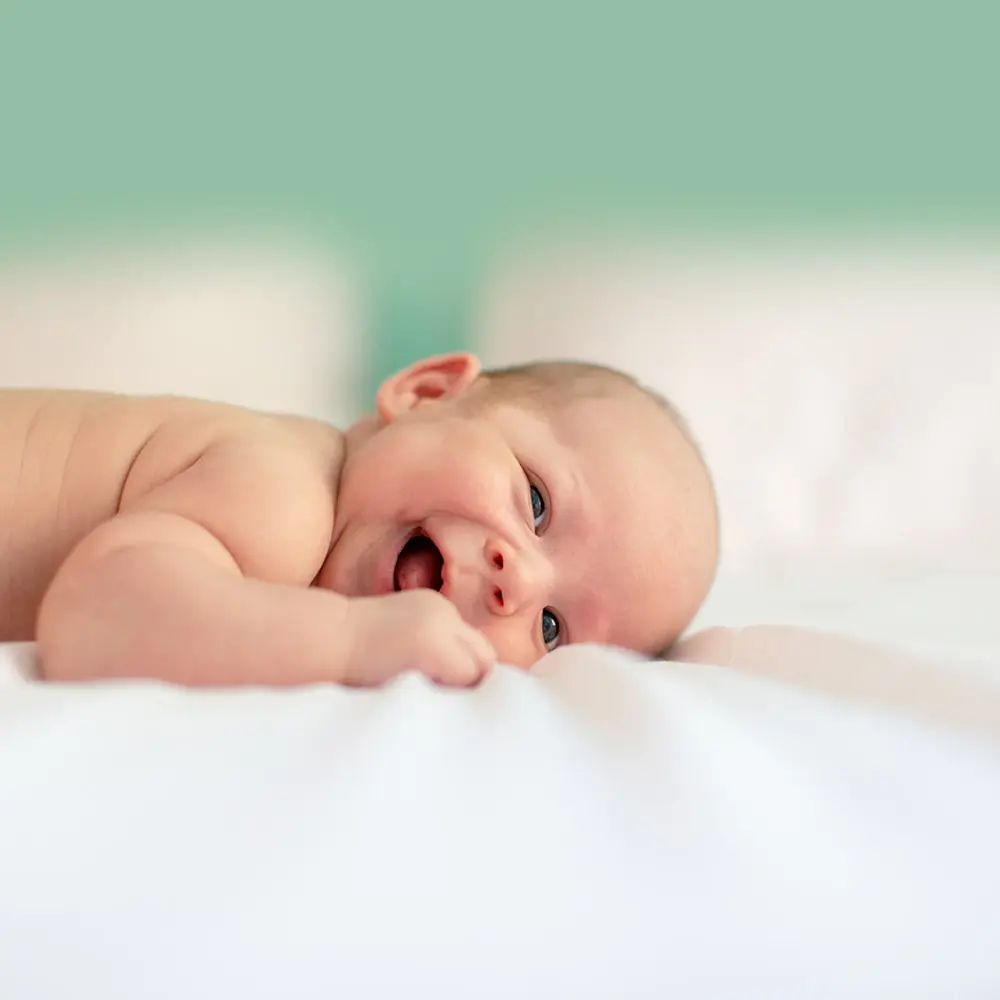 happy baby laying on a mattress