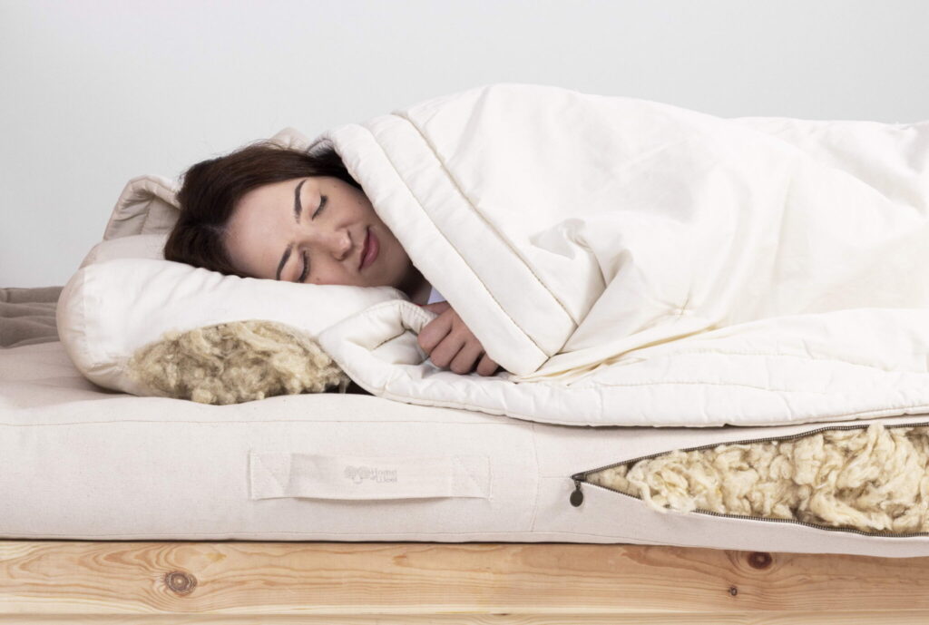 kvinna som sover på en madrass av ull och en kudde av ull täckt med en täcke