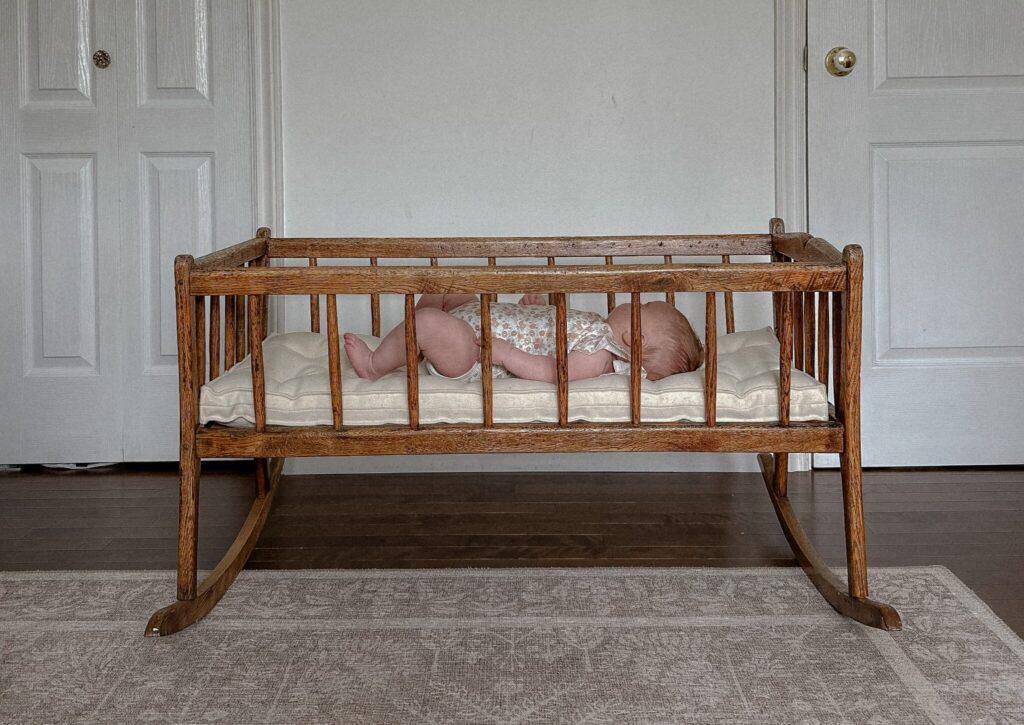 baby som sover i en gyngende barneseng med en madrass av ull