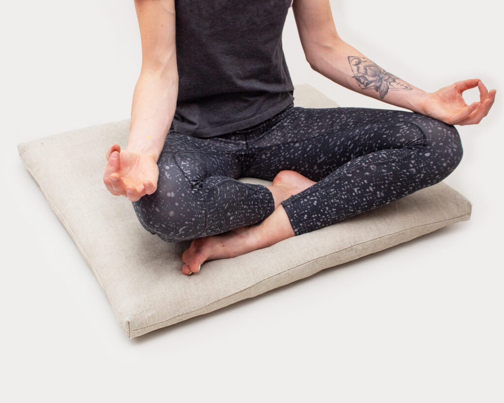 kvinna som gör yoga på en zabuton av ull