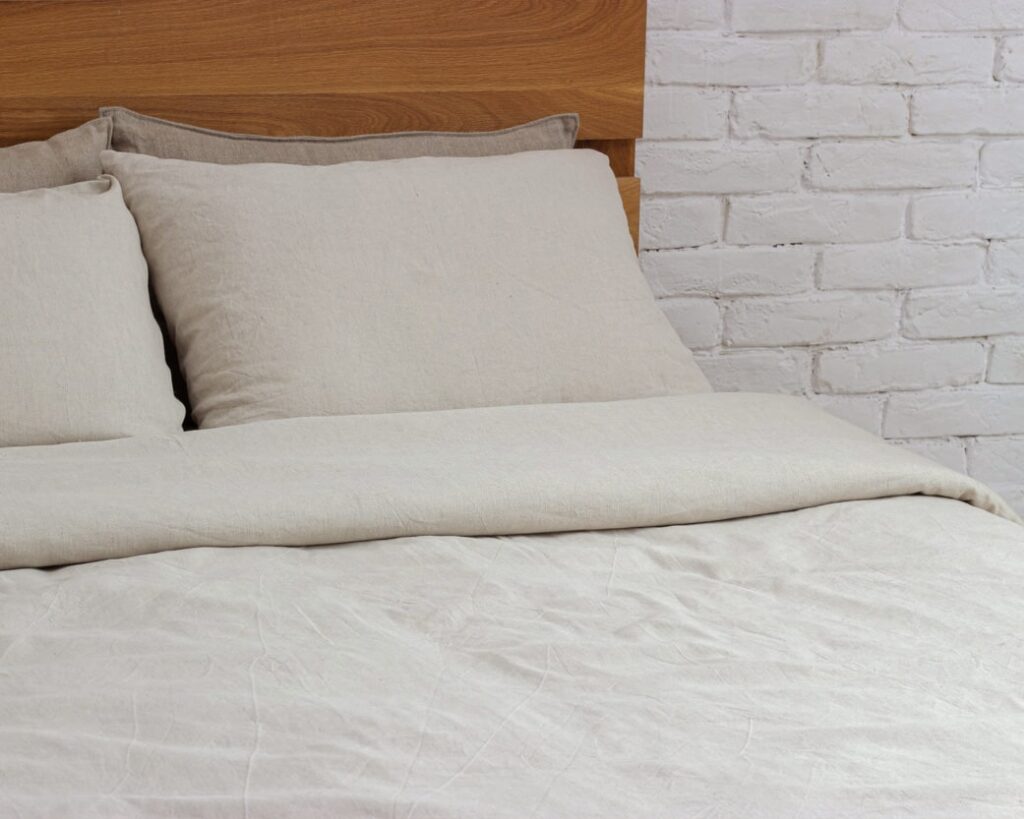 linne kudde och sängkläder mot rustik vägg