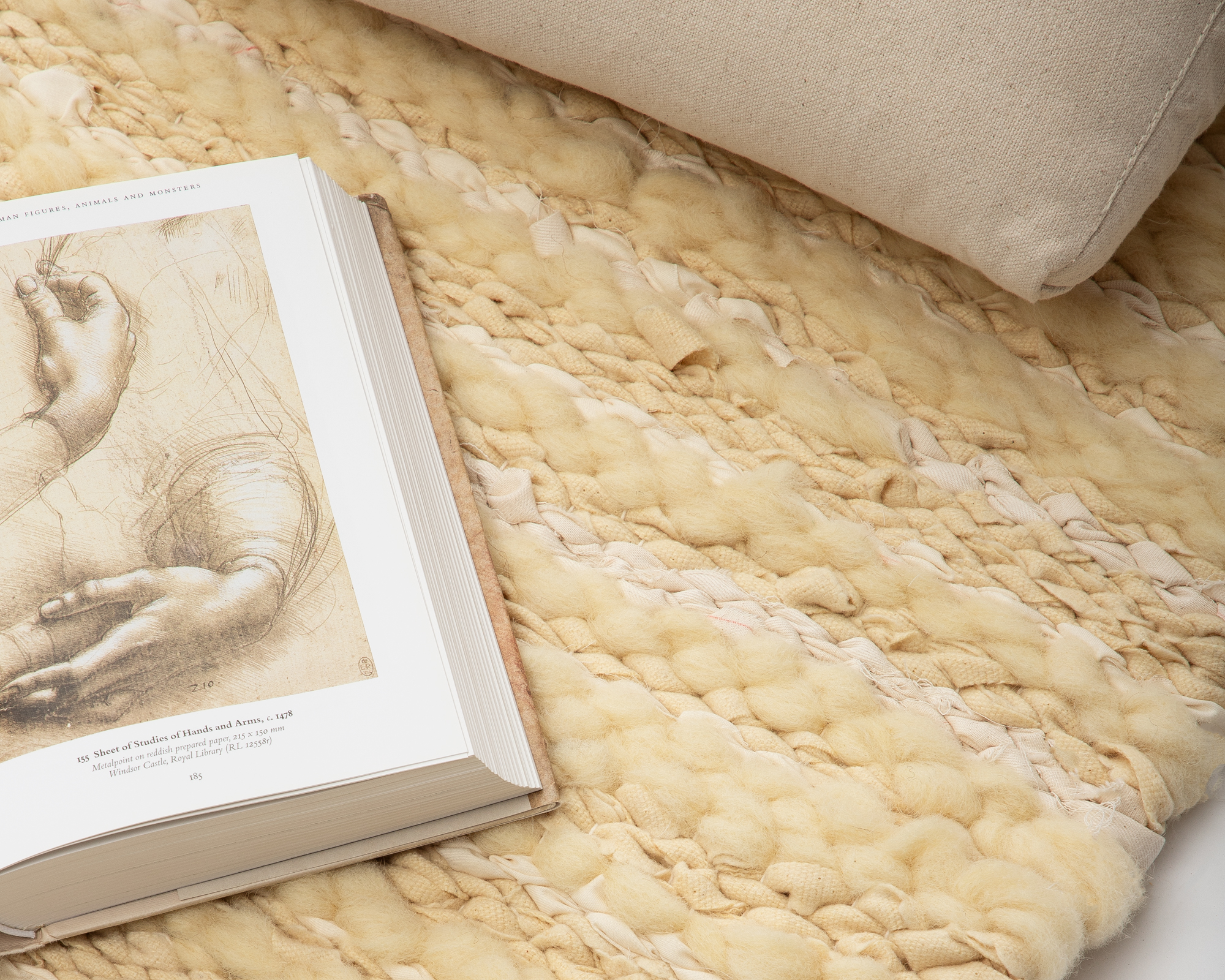 libro y un cojín sobre una alfombra tejida