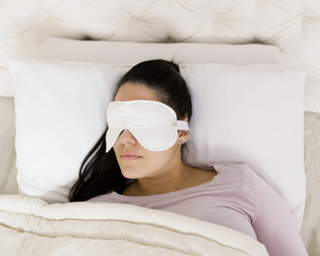 kvinde med en uld-søvnmaske liggende på en uldpude dækket med en ulddyne