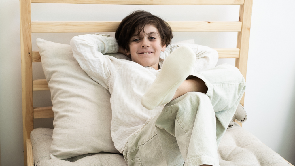 kid smiling while laying on a home of wool mattress and pillow on his back