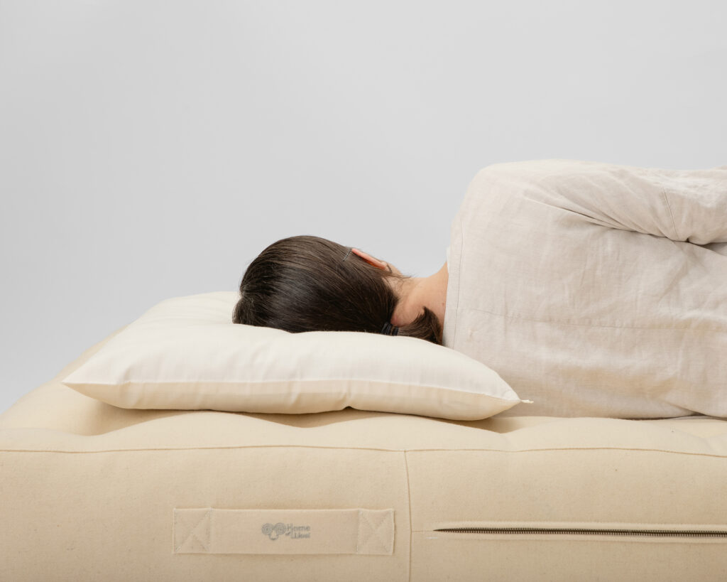 woman laying on her side on a home of wool wool mattress and a thin wool pillow