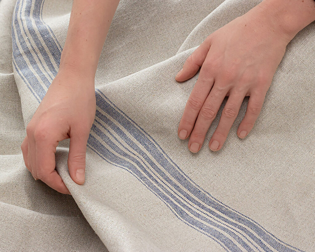 hands holding 100% linen blue stripes fabric