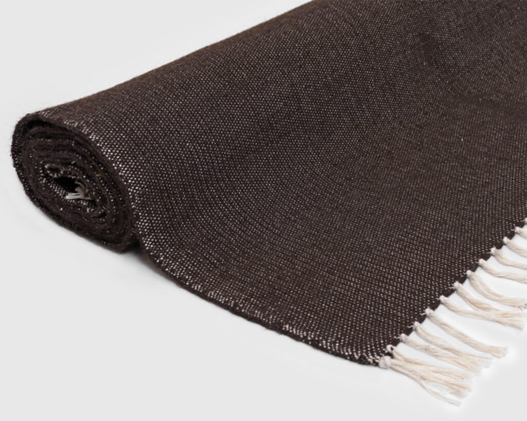 rolled up dark brown flat woven wool rug