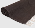 rolled up dark brown flat woven wool rug