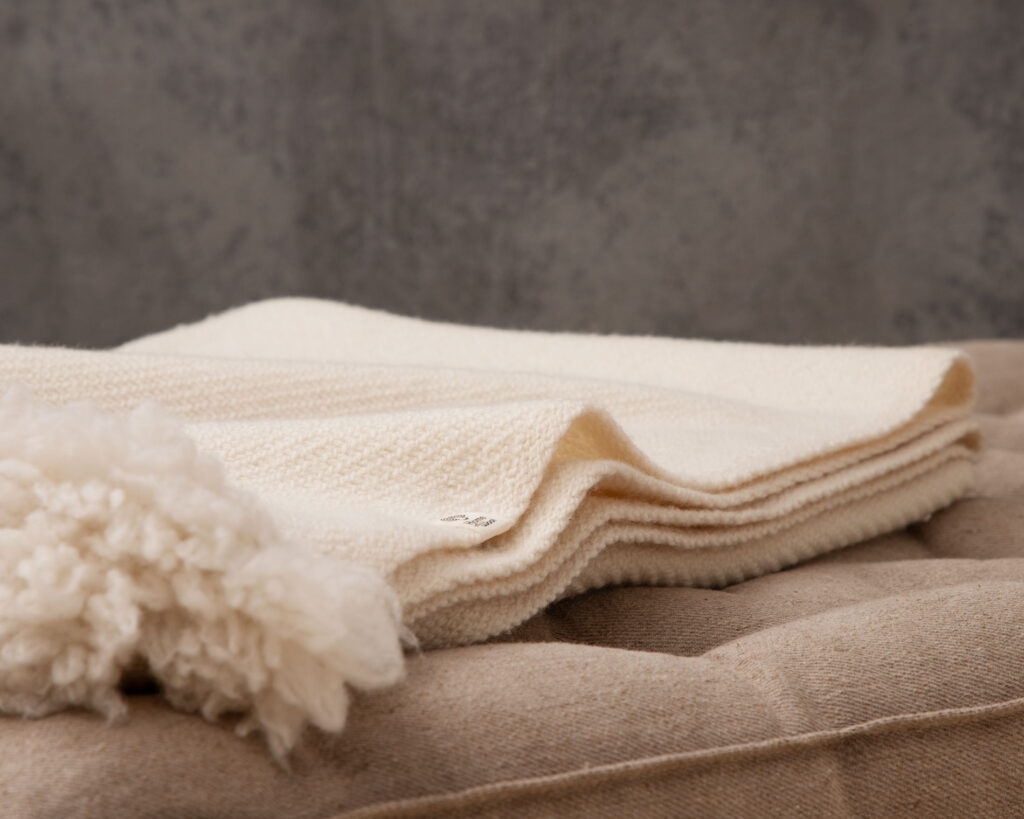 folded merino wool baby blanket on top of mattress