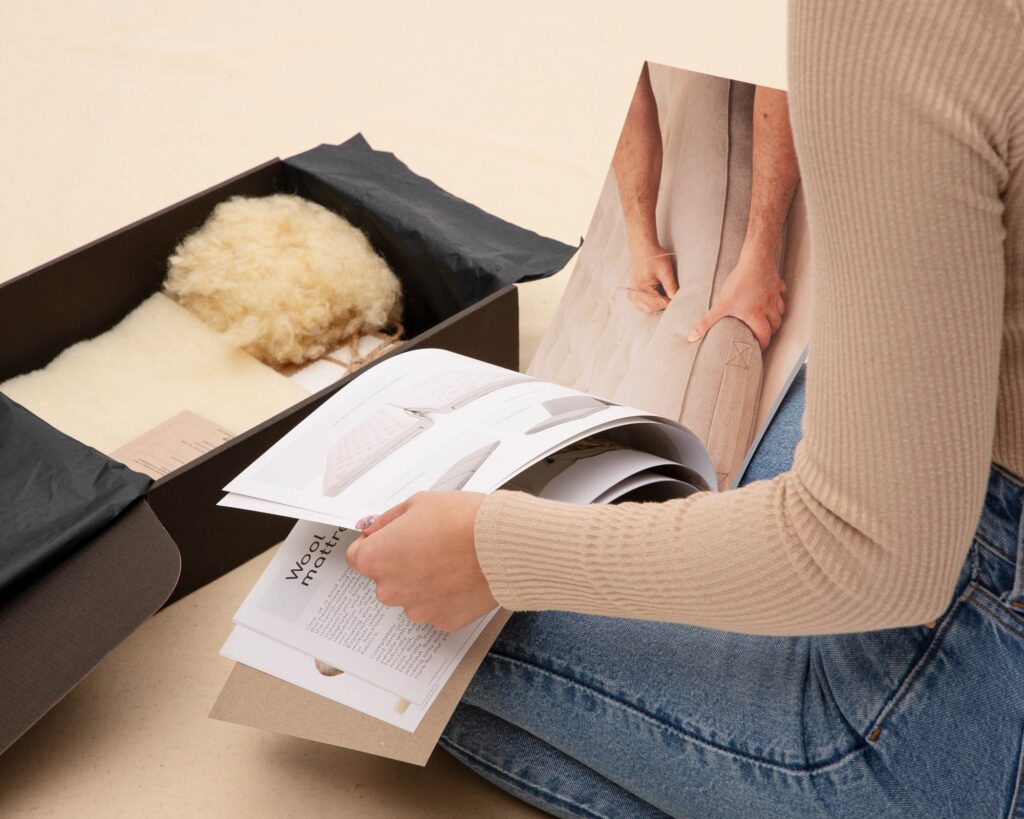 product box with fabrics and wool and a person looking through the catalogue