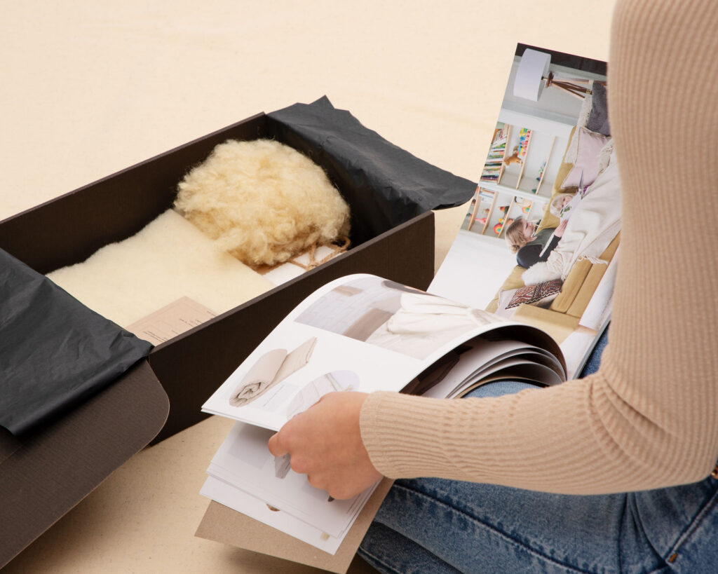 product box with fabrics and wool and a person looking through the catalogue