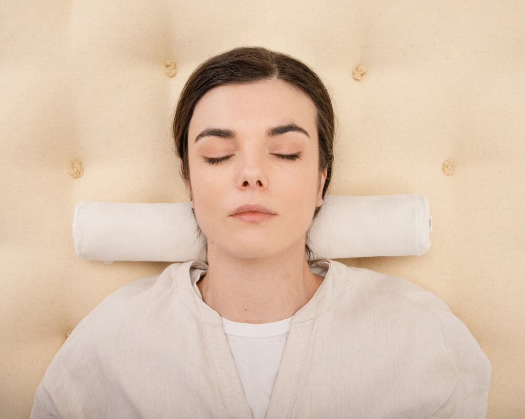 wool neck roll pillow on a wool mattress and a person sleepiung