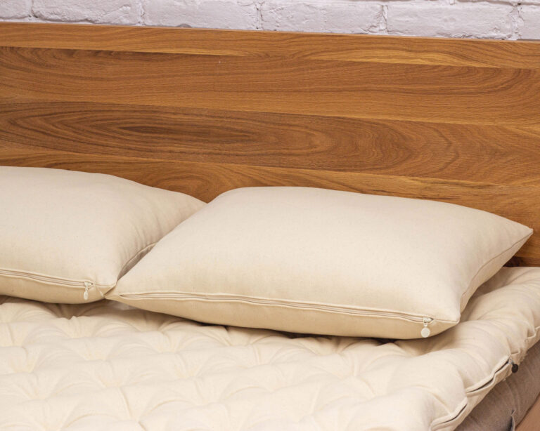 kaksi tyynyä sängyssä, joissa on villatyynynsuojukset.