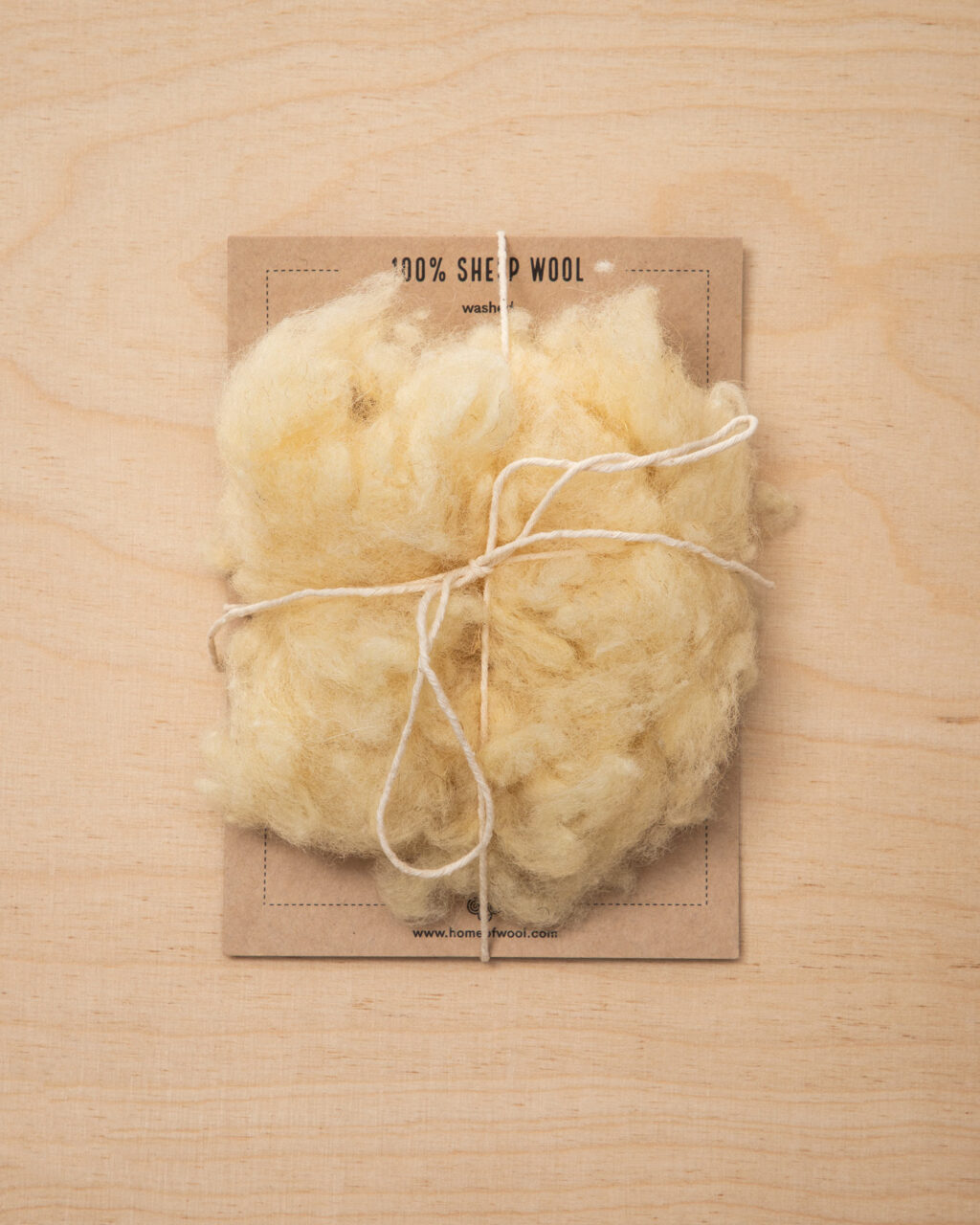 handvol wol op een stuk karton met merknaam, vastgebonden met touw