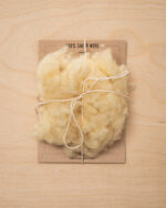 handvol wol op een stuk karton met merknaam, vastgebonden met touw