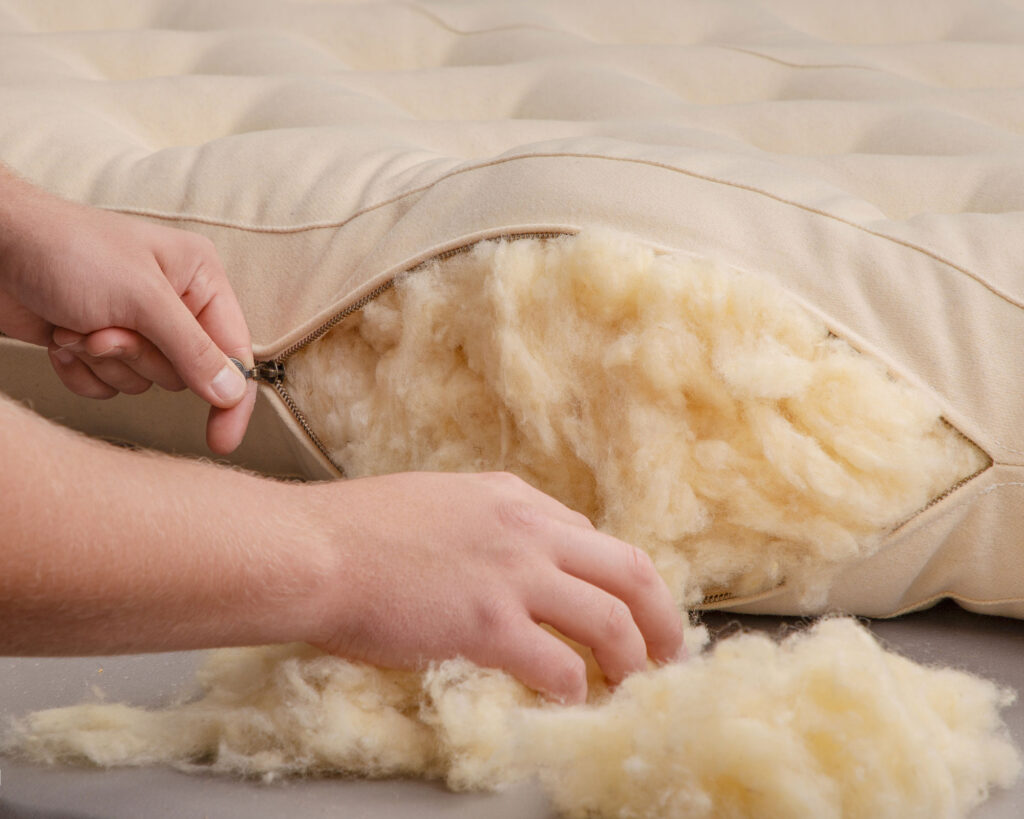 hands stuffing a mattress with wool